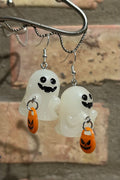 Smiling acrylic ghost earrings holding jack-o-lantern trick or treat bags. Earring are hanging from a silver hook in front of a light brown brick background.